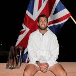 Cameron Norrie sitting in front of the British flag and his Indian Wells trophy