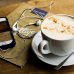 Phone and earphones by a cup of coffee